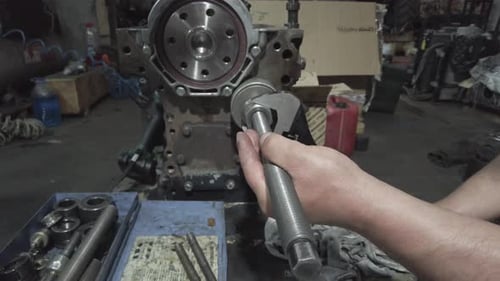 Mechanic tightening bolt of engine block with wrench