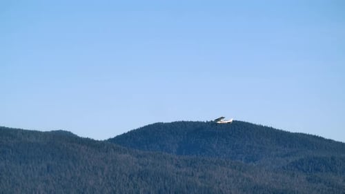 Small Airplane Flies Over Mountains on Sunny Day