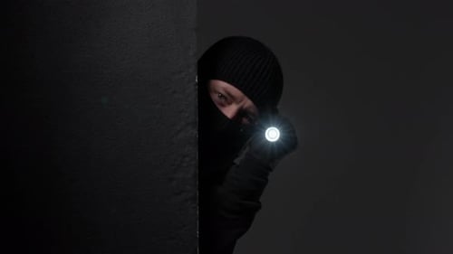 Figure in Dark Clothing Holding a Flashlight