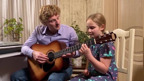 Guitar Lesson with Man and Young Girl Indoors
