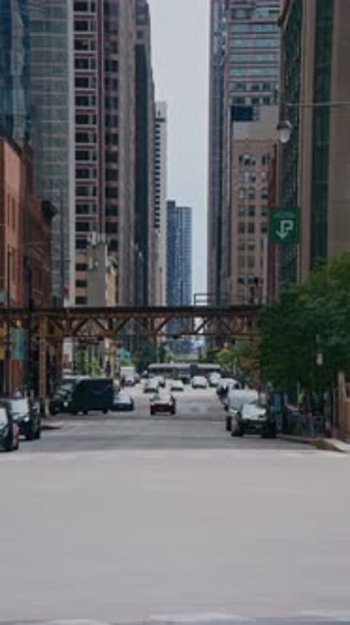 Handheld Scene of Downtown Chicago Street with Busy Traffic and Iconic L Train Tracks Overhead