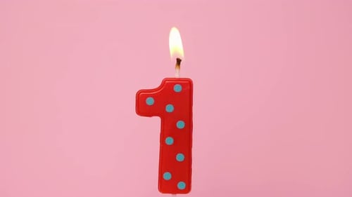 One Years Anniversary Video Banner with Burning Spotted Red and Green Number One Candle on Light
