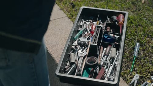 Open toolbox with assorted hand tools outdoors