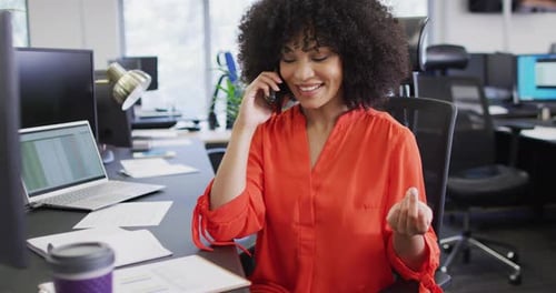 Happy african american businesswoman talking on smartphone in office, slow motion