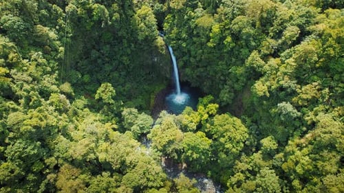 Aerial view of a tall rainforest waterfall on sunny summer day in Costa Rica