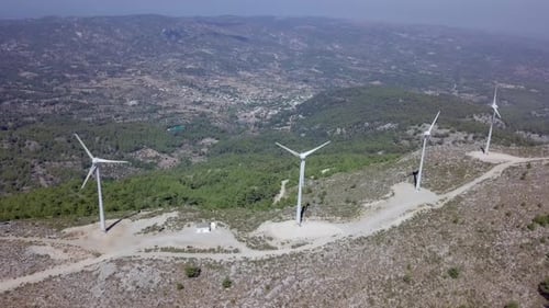 Imagens aéreas de turbinas eólicas girando, em uma floresta montanhosa ao redor