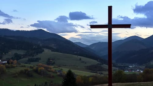 Christian Cross in Mountain Rural Landscape Clouds in Blue Sky at Dusk