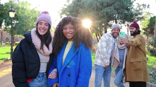 On Foreground Two Multiracial Young Women Smiling and Laughing Together Looking at Camera at