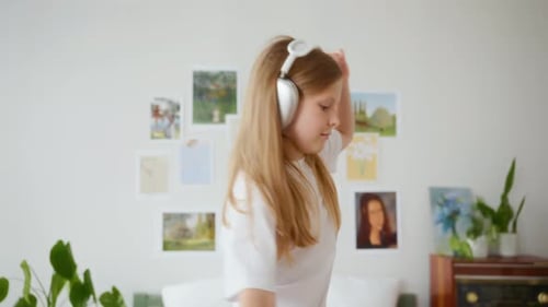 Girl Dancing Happily with Headphones in Bedroom