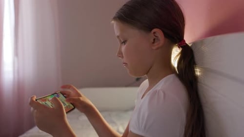 Girl Playing Game on Smartphone in Bedroom