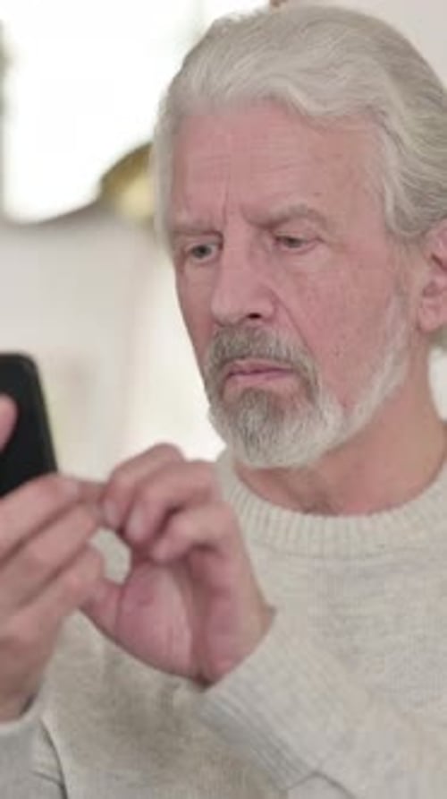 Senior Man Using Phone, Close-Up Portrait Indoors