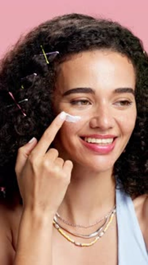 Smiling Woman Applying Skincare Cream to Her Face