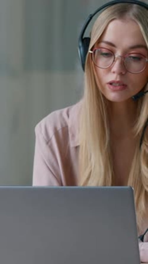 Caucasian Business Woman Talking Video Call Writing Notes Wearing Headset in Office Businesswoman