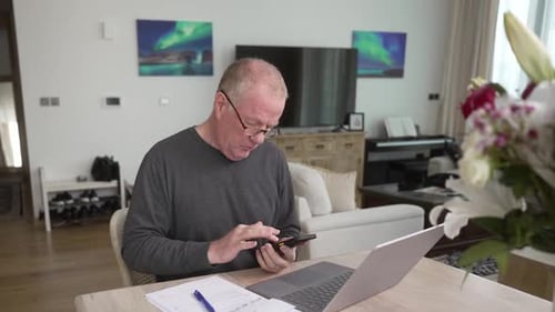 Man Uses Phone and Laptop at Home