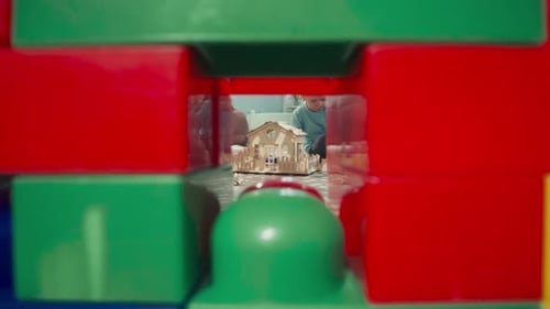 Niño construye una pared con bloques de colores sentado cerca de la casa