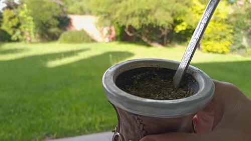 Pouring hot water from thermos into Mate while holding it in hand, traditional drink from Argentina,