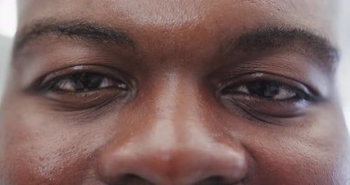 Close up of portrait of happy african american man looking at camera in slow motion