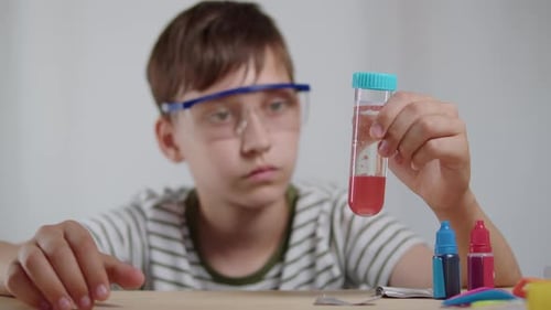 Niño inspeccionando un tubo de ensayo con líquido rojo