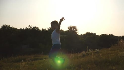 Young Boy with Raised As Airplane Hands Running on Green Grass at the Field on Sunny Day