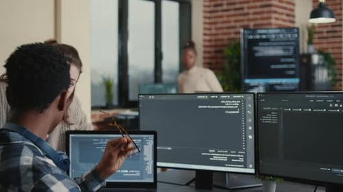 Softwareentwickler feiert Codeerfolg am Schreibtisch mit mehreren Monitoren