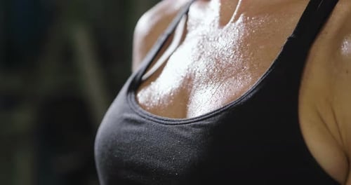 Close up of the body of a sporty and fit woman, who recovers her energy after sweating at the end