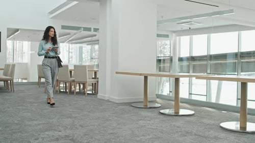 Woman Walks with Tablet in Modern Office Space