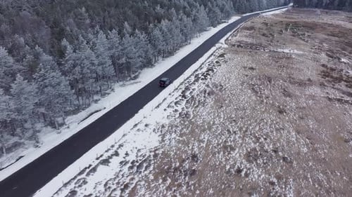 Aerial View of Black Car Driving Along Mountain Pass Vehicle Travels on a Street That Separates a