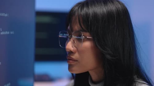 Asian woman programmer wearing glasses reading source code