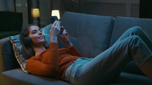 Junge Frau liegt zu Hause mit ihrem Smartphone-Gerät auf der Couch Frau ruht sich aus