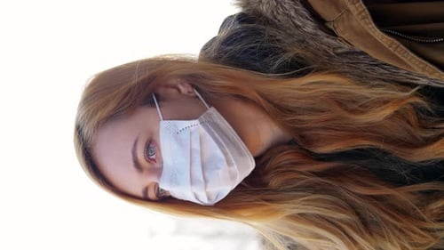 Young woman in medical mask outdoors protects herself during coronavirus pandemic