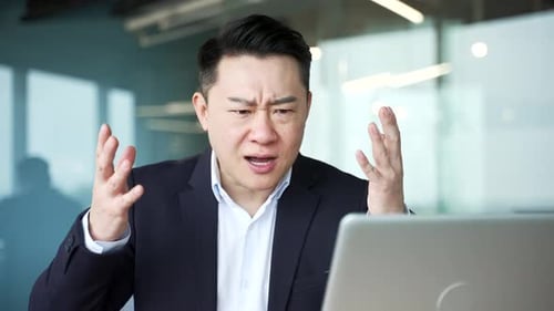Frustrated Businessman Arguing at Laptop in Office