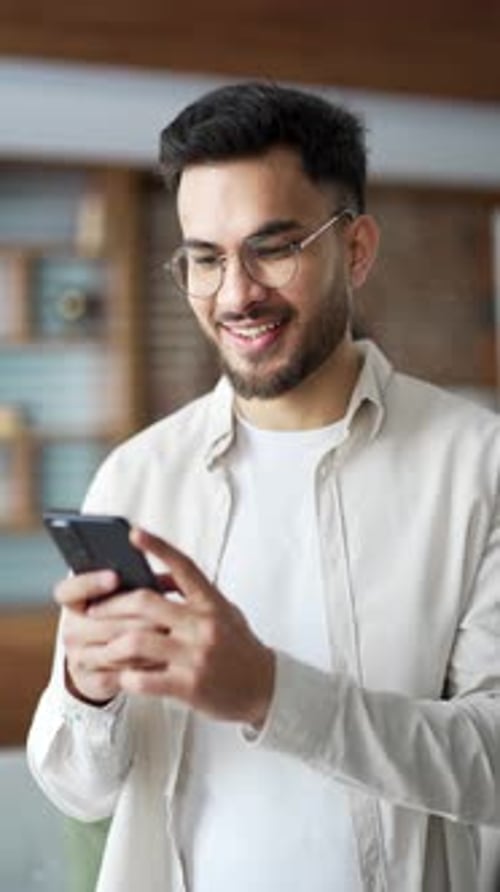Young Adult Smiling Using Smartphone Indoors