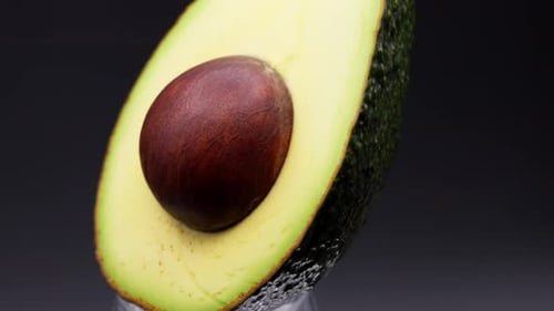 Half an avocado spinning on a black background.