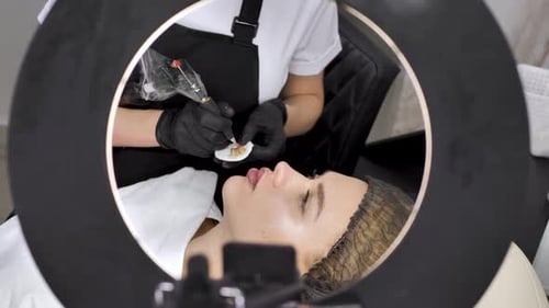 Eine Kosmetikerin trägt in einem Schönheitssalon Permanent Make-up auf die Lippen auf