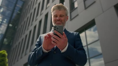 Man Uses Phone Outside Modern Office Building
