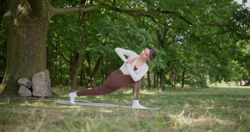 Young Beautiful Athletic Woman in Sportswear Doing Stretching and Warming Up in the Park Near a Tree