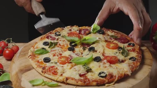 Chef uses a pizza paddle to lift a slice of pizza and in the process stretches the cheese.
