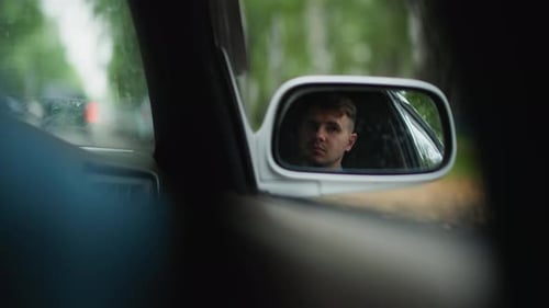 Man reflected in car mirror during daytime drive