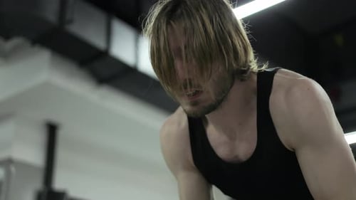 Hombre sudoroso haciendo ejercicio con cuerdas de combate durante el entrenamiento de cross fit en interiores