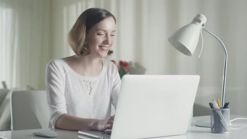 Woman Celebrates Success Using Laptop at Home