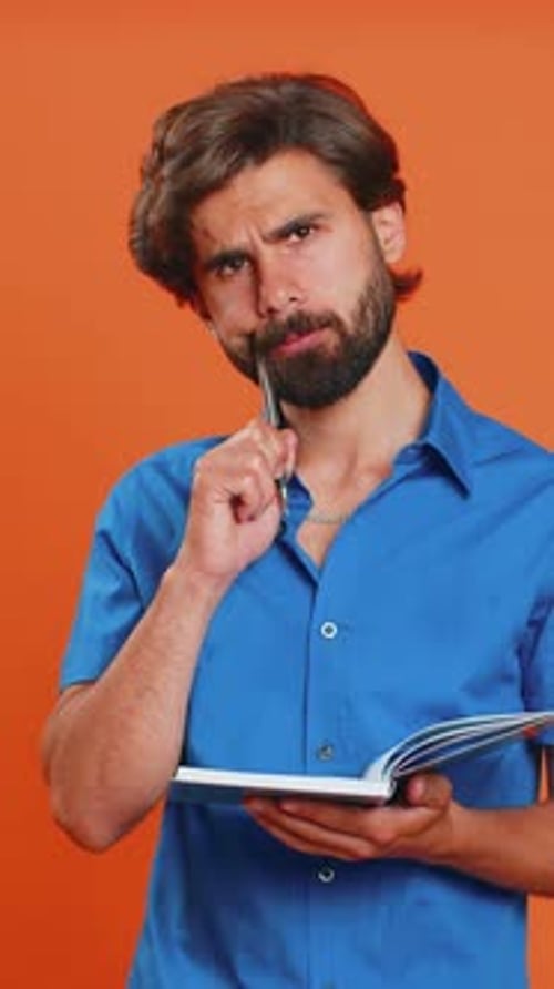 Man in Blue Shirt Writes in a Notebook