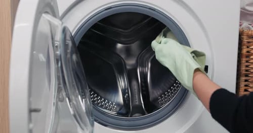 Cleaning Washing Machine with Gloved Hand and Cloth