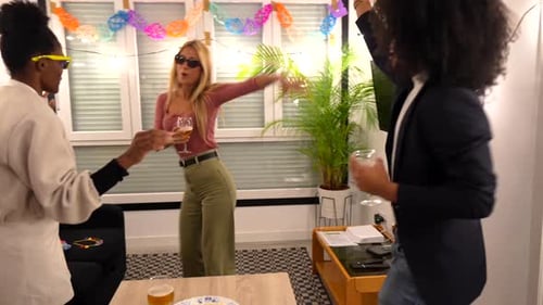 Amigos multiétnicos dançando e bebendo na festa em casa