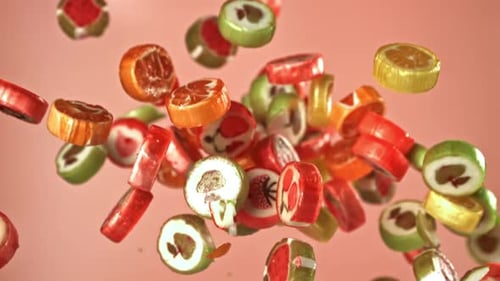 Colorful Fruit Candy Pieces Falling on Pink Background