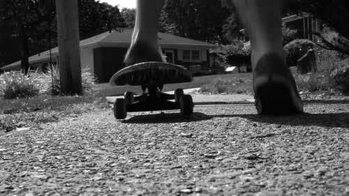 Person Riding Skateboard on Sidewalk, Black and White