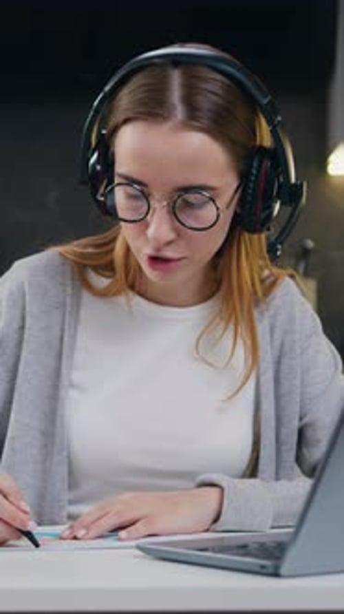 Woman with Headset Attends Online Meeting and Takes Notes