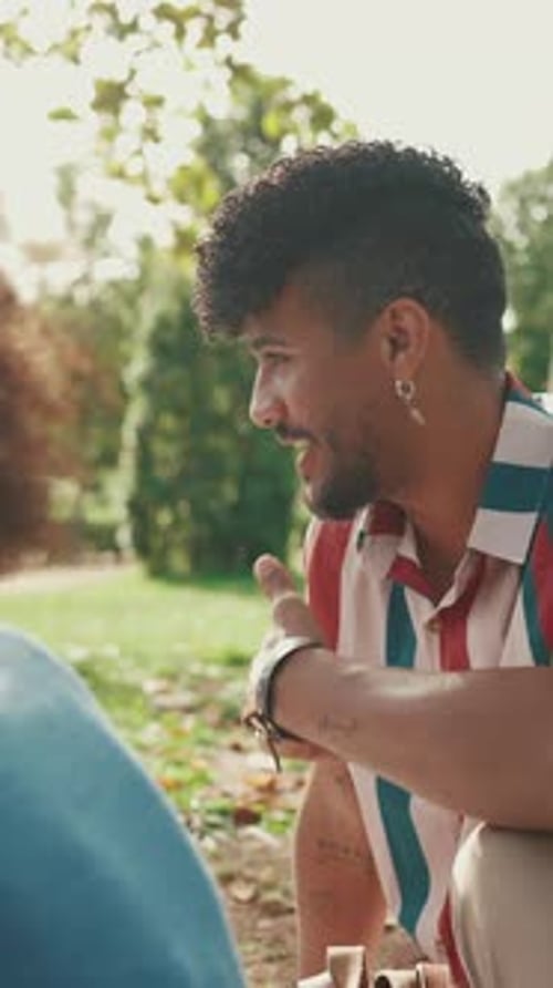 Close-up of young man sitting in park having picnic, talking with friends