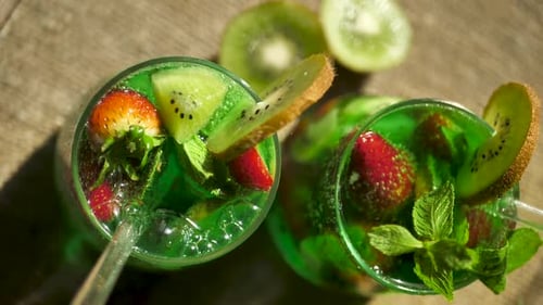 Top View Two Glasses Filled with Sparkling Soda Infused with Kiwi and Strawberries and Using Glass