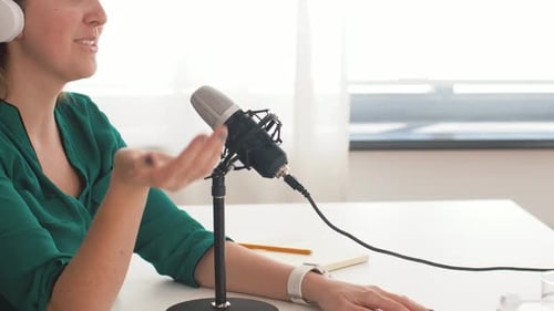 Young woman with microphone recording a podcast in a radio studio