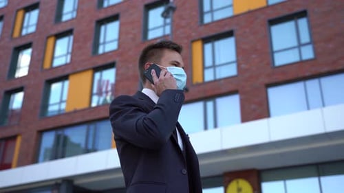 European Man Wearing Surgical Face Mask Using Smartphone in the City